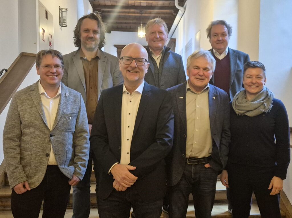 Eine Gruppe von Personen lächelt für ein Gruppenfoto in einem Gasthaus.