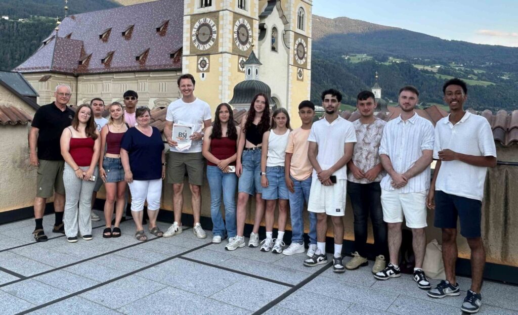 Ein Gruppenfoto von Jugendlichen in Brixen. Eine Person hält ein Dokument mit dem BSJ-Logo in der Hand.