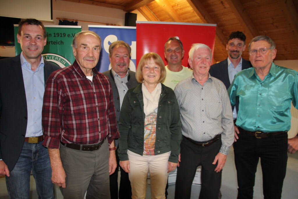 Mehrere Personen lächeln für ein Gruppenbild in die Kamera.