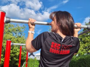 Sportlerin des SKC'67 Eggolsheim im schwarzen Trikot (mit Vereinsname) absolviert Klimmzug.