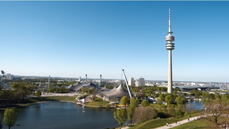 Abbildung des Münchener Olympiaparks mit Blick auf Stadion, See und Fernsehturm